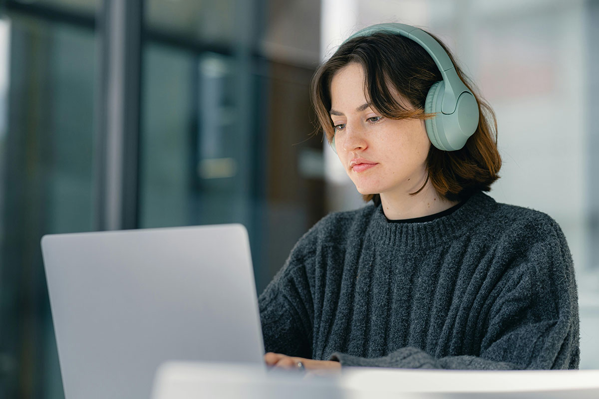 Woman with headphones on working on a laptop